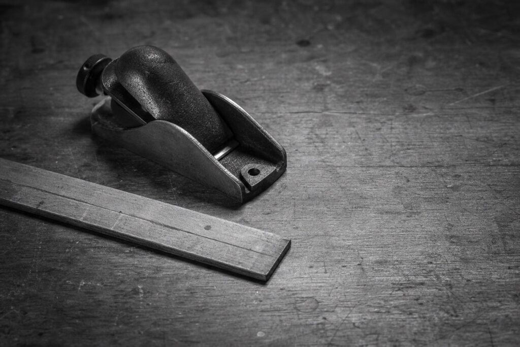 A well-used hand plane and ruler resting on a craftsman’s workbench.