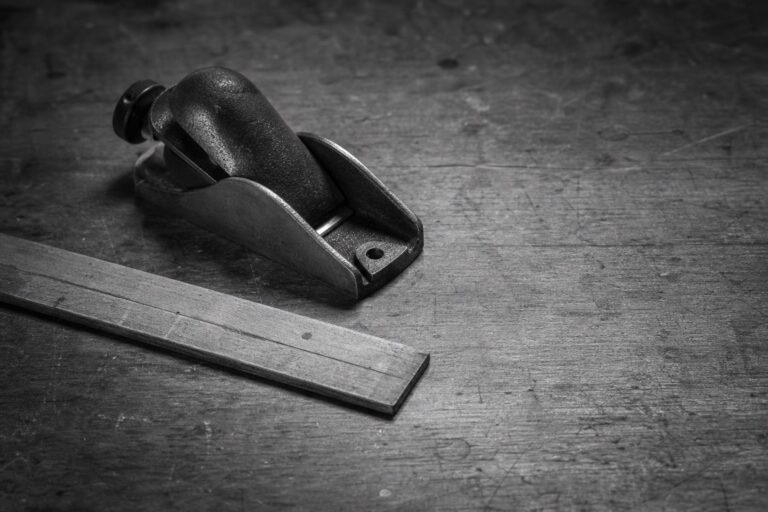 A well-used hand plane and ruler resting on a craftsman’s workbench.