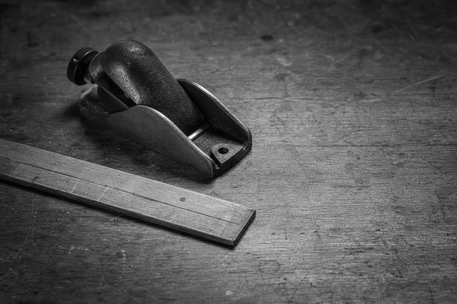 A well-used hand plane and ruler resting on a craftsman’s workbench.