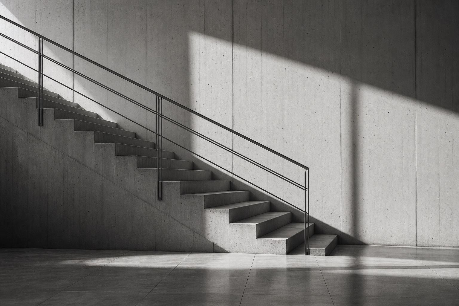 A concrete staircase and handrail shaped by long geometric shadows.