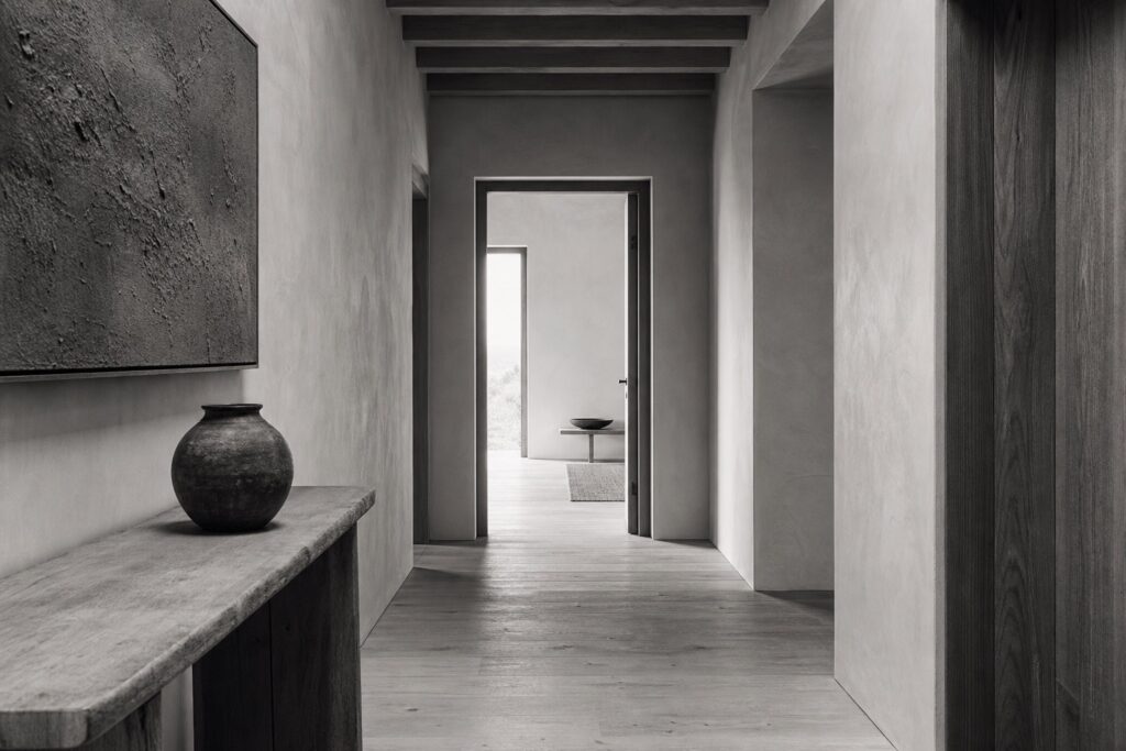 A quiet light-filled corridor with an open doorway at the end.