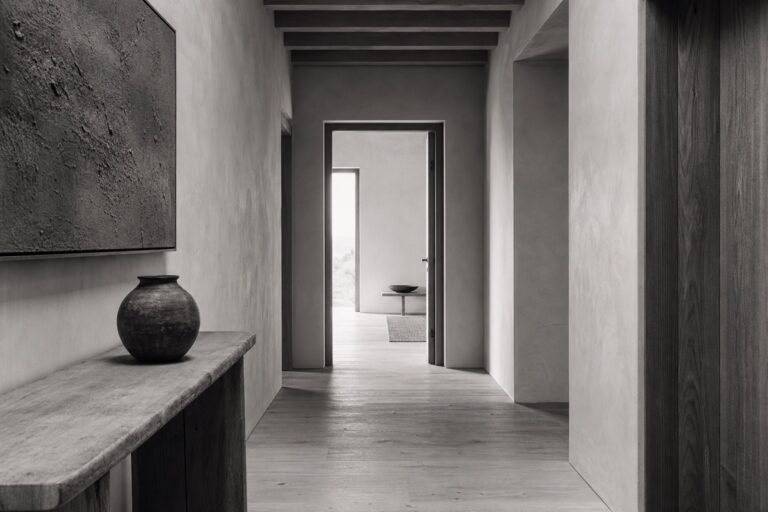A quiet light-filled corridor with an open doorway at the end.